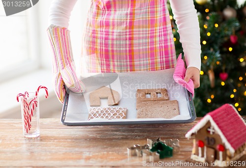 Image of closeup of woman with gingerbread house on pan