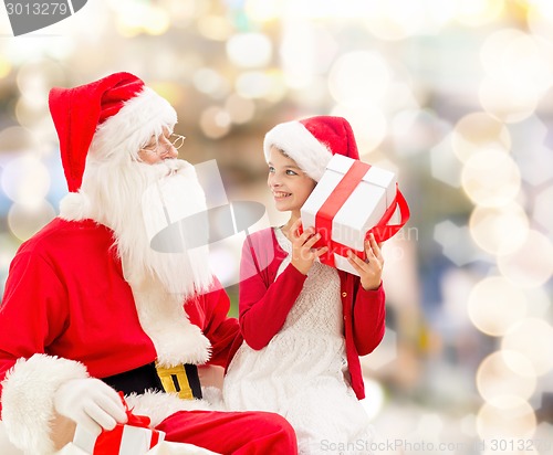 Image of smiling little girl with santa claus and gifts