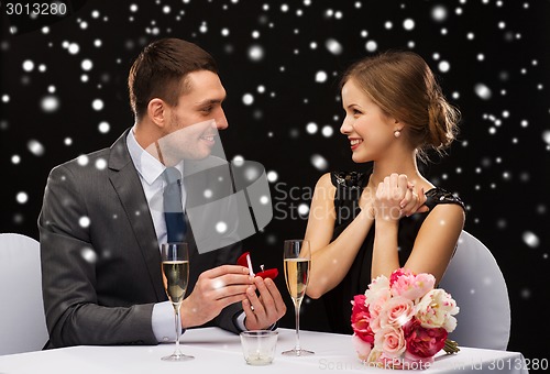 Image of smiling couple with red gift box at restaurant