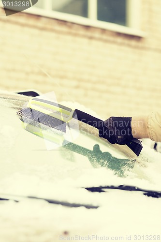 Image of closeup of man cleaning snow from car