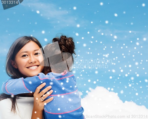 Image of smiling little girl and mother hugging indoors