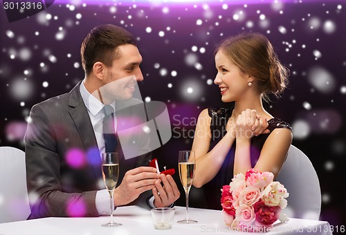 Image of smiling couple with red gift box at restaurant