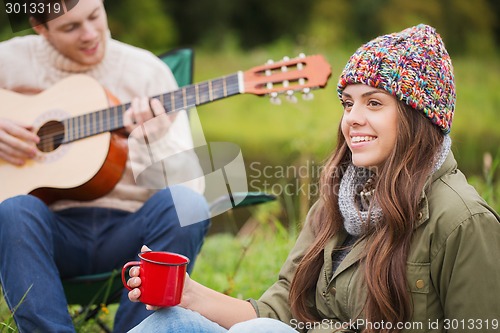 Image of smiling couple with guitar in camping