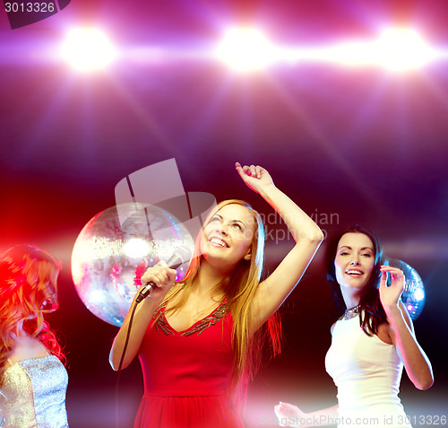 Image of three smiling women dancing and singing karaoke