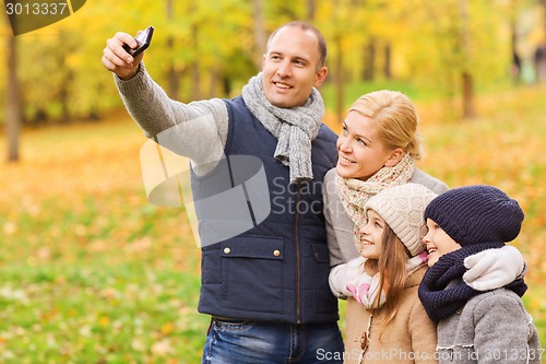 Image of happy family with camera in autumn park