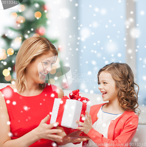 Image of smiling mother and daughter with gift box at home