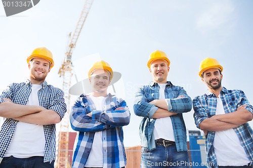 Image of group of smiling builders in hardhats outdoors