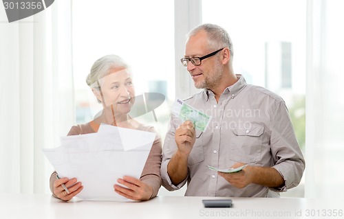 Image of senior couple with money and calculator at home