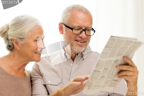 Image of happy senior couple reading newspaper at home