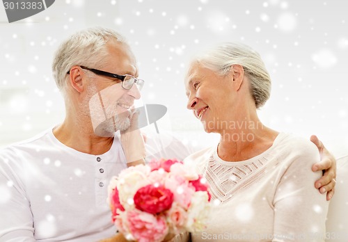 Image of happy senior couple with bunch of flowers at home