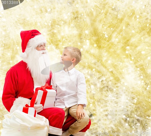 Image of smiling little boy with santa claus and gifts