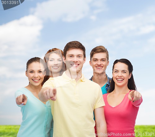 Image of group of smiling teenagers over blue sky and grass