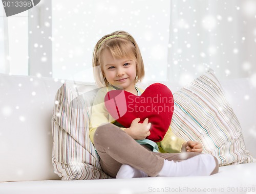 Image of smiling girl with big red heart sitting on sofa