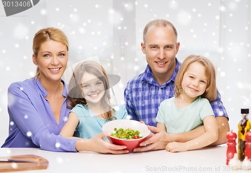 Image of happy family with two kids showing salad in bowl