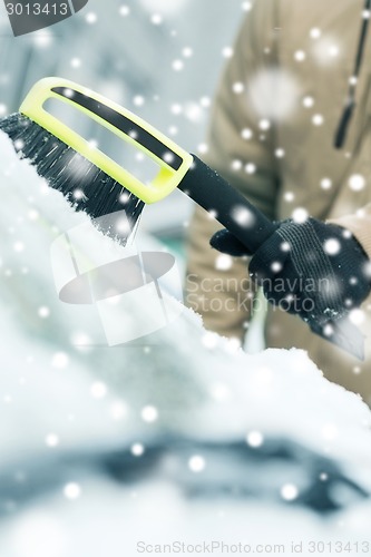 Image of closeup of man cleaning snow from car