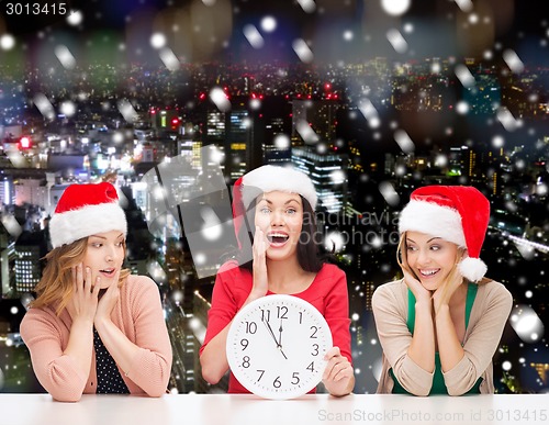 Image of smiling women in santa helper hat with clock