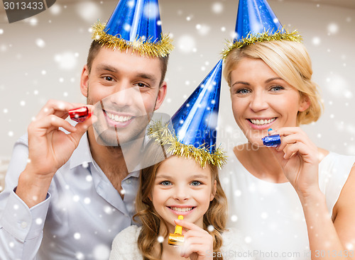 Image of smiling family in party hats blowing favor horns