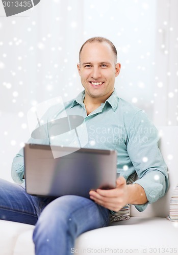 Image of smiling man working with laptop at home