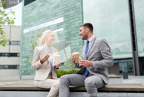 Image of smiling businessmen with paper cups outdoors