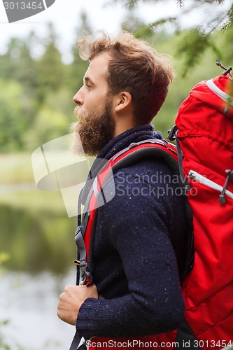 Image of smiling man with beard and backpack hiking