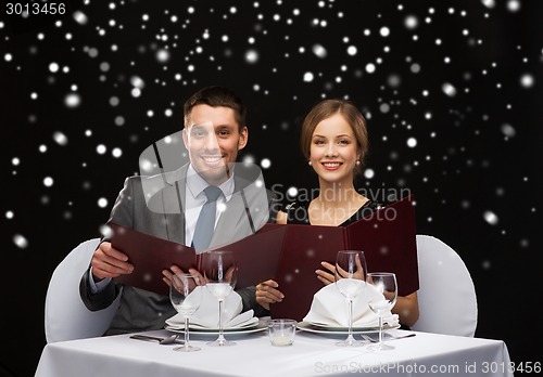 Image of smiling couple with menus at restaurant