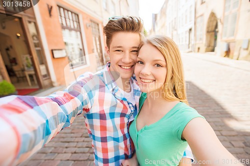 Image of smiling couple with smartphone in city