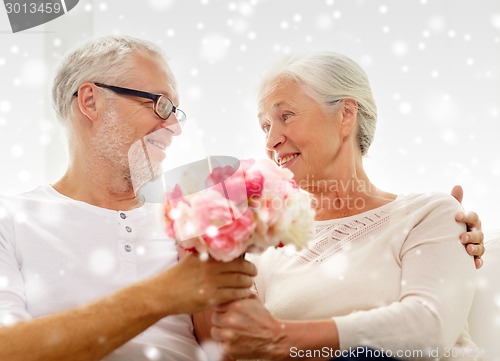 Image of happy senior couple with bunch of flowers at home