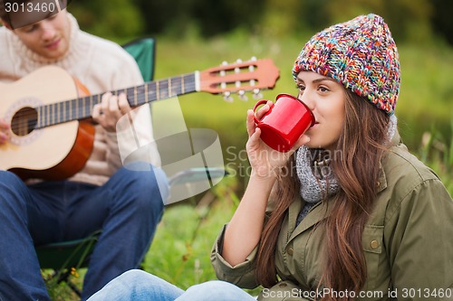 Image of smiling couple with guitar in camping