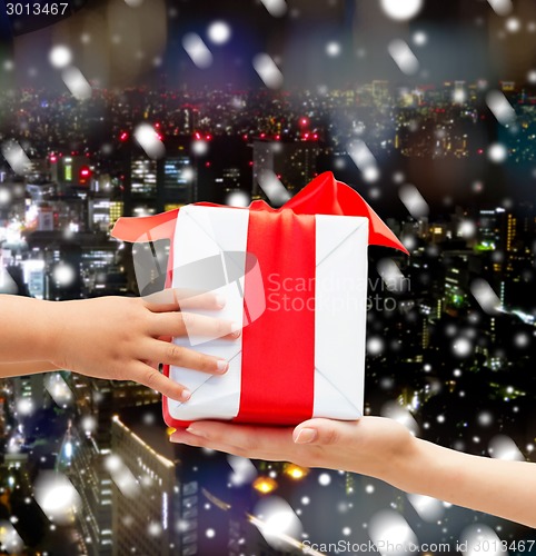 Image of close up of child and mother hands with gift box