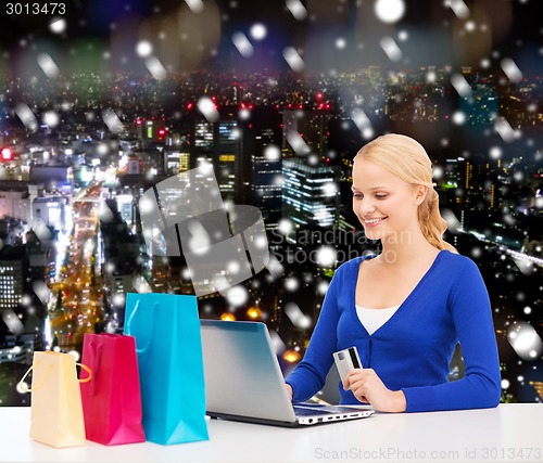 Image of smiling woman with credit card and laptop
