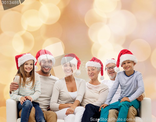 Image of happy family in santa helper hats sitting on couch