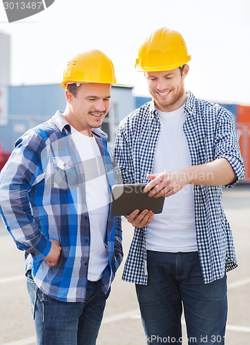 Image of smiling builders in hardhats with tablet pc