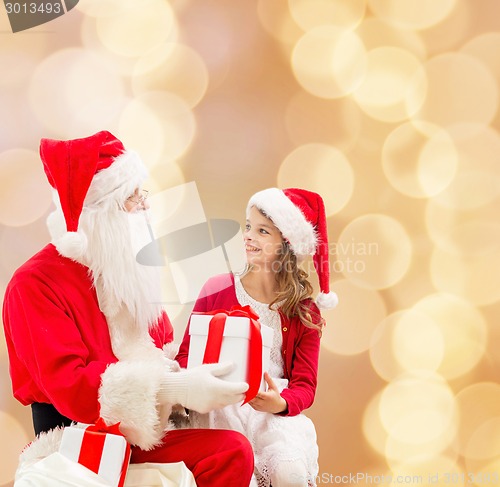 Image of smiling little girl with santa claus and gifts