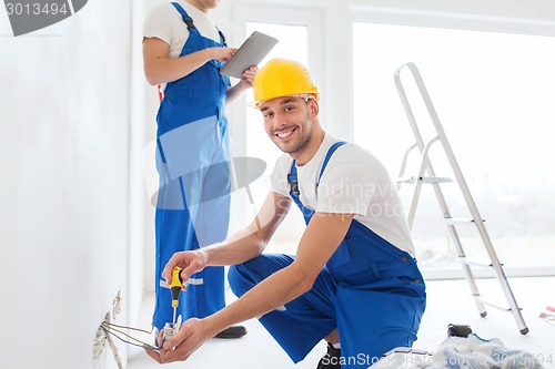 Image of builders with tablet pc and equipment indoors