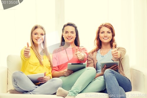 Image of three smiling teenage girls with tablet pc at home