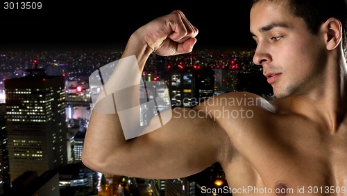 Image of close up of young man showing biceps