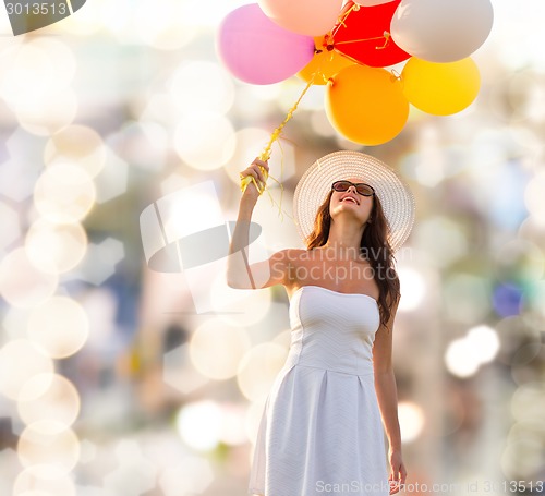 Image of smiling young woman in sunglasses with balloons