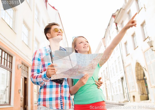 Image of smiling couple with map and photo camera in city