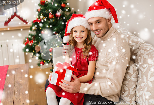 Image of smiling father and daughter with gift box at home