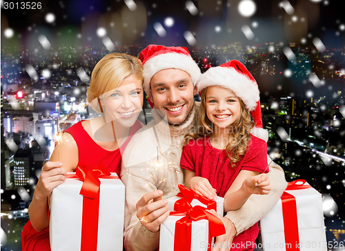 Image of happy family in santa helper hats with gift boxes