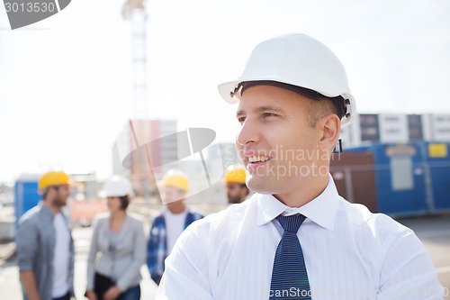 Image of group of smiling builders in hardhats outdoors