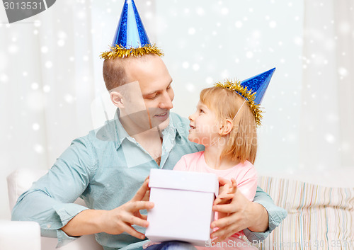 Image of father and daughter in party caps with gift box