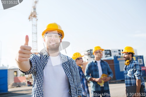 Image of group of smiling builders in hardhats outdoors