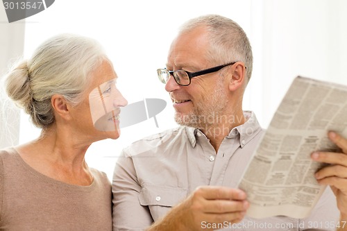 Image of happy senior couple reading newspaper at home