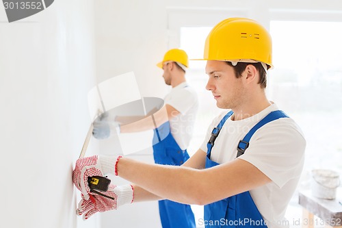 Image of group of builders with measuring tape indoors