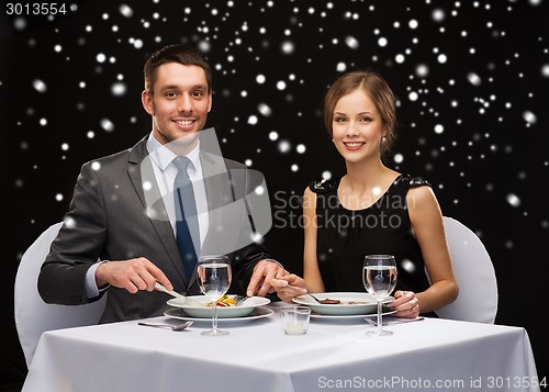 Image of smiling couple eating main course at restaurant