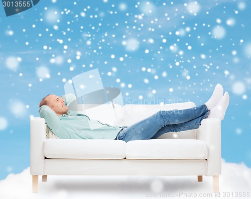 Image of smiling man lying on sofa