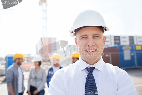 Image of group of smiling builders in hardhats outdoors