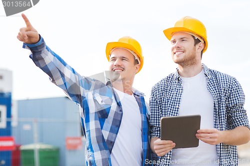 Image of smiling builders in hardhats with tablet pc