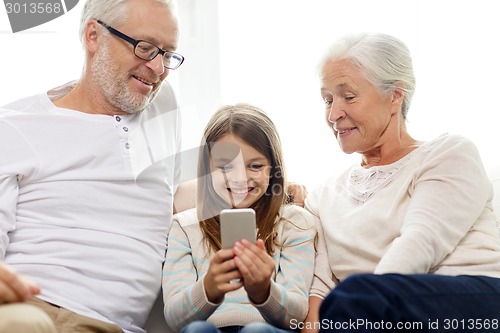Image of smiling family with smartphone at home